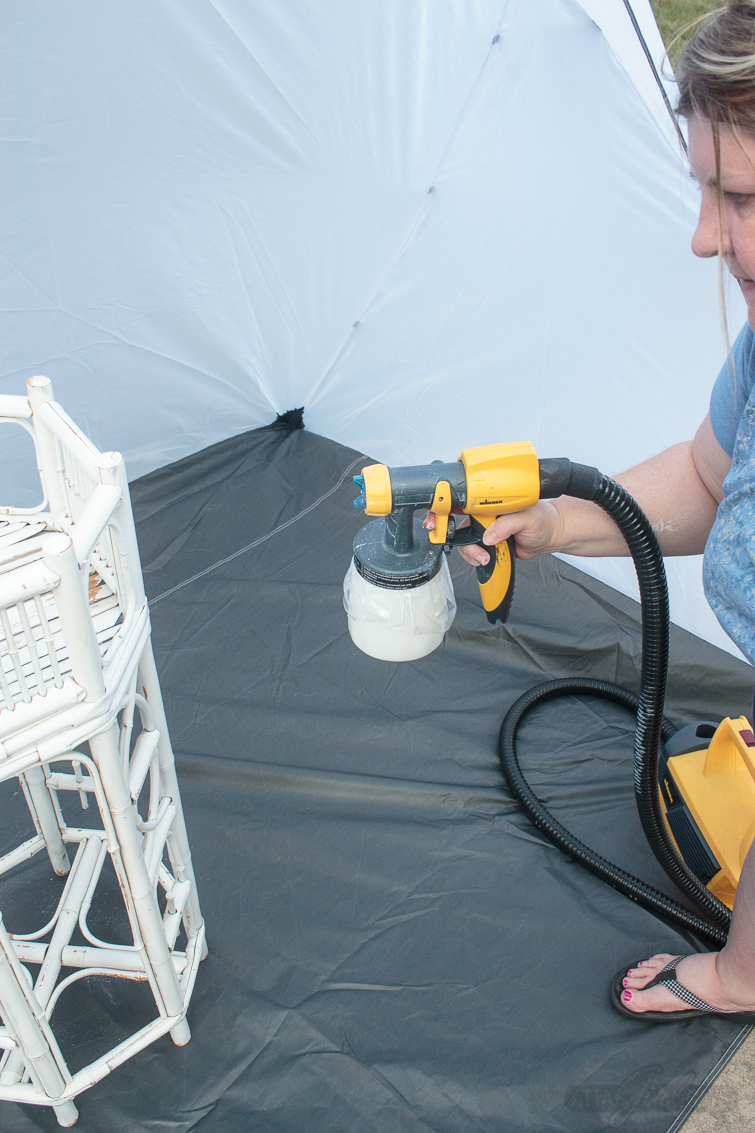 woman painting bamboo furniture with a paint sprayer