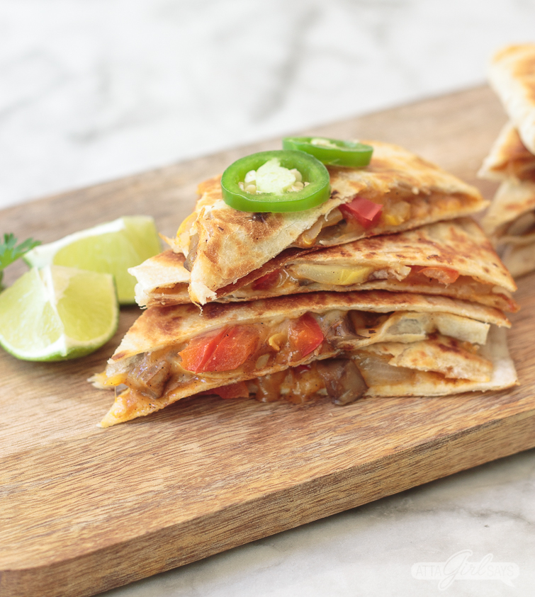 stack of veggie fajitas, topped with jalapeno slices, on a wooden board
