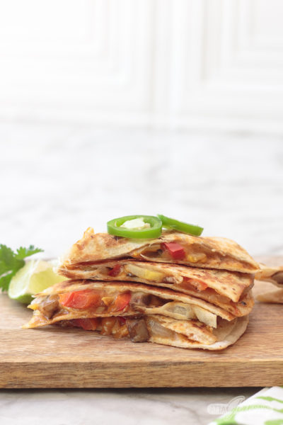 stack of veggie fajitas, topped with jalapeno slices, on a wooden board
