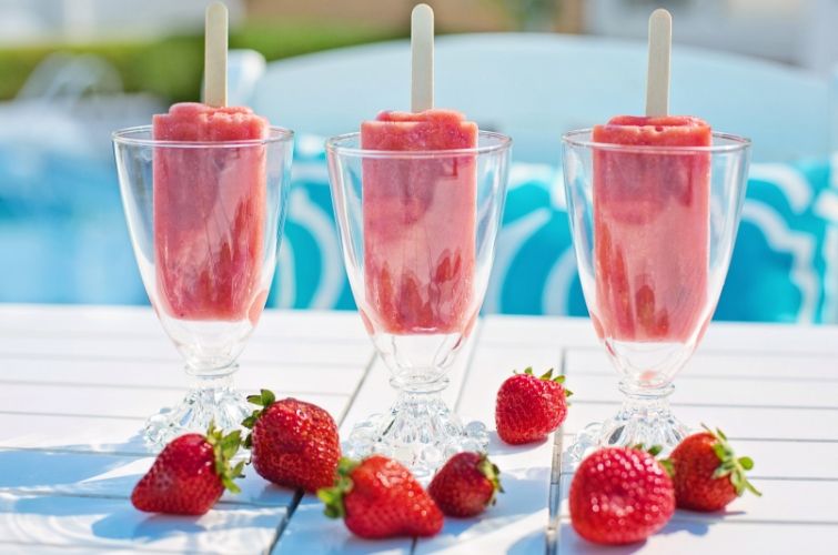 three strawberry popsicles in wine glasses