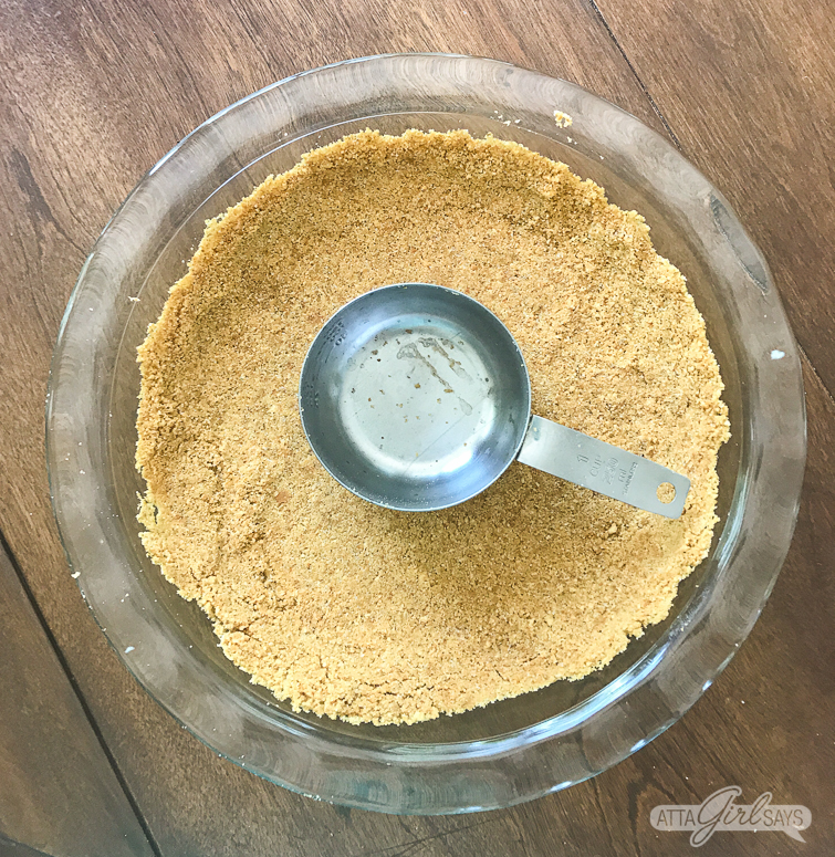 pressing graham cracker crumbs into a pie plate to make cherry yum yum
