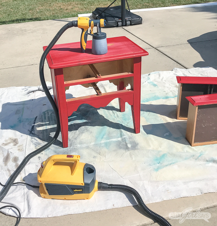 paint sprayer sitting on a red nightstand with two drawers on a dropcloth