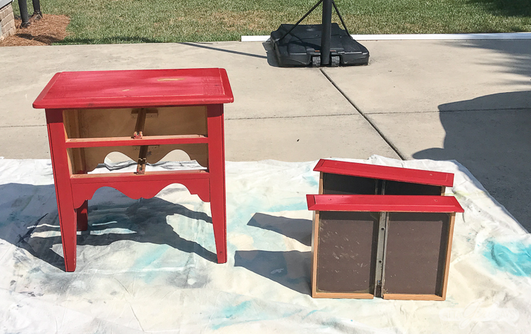 red nightstand with two drawers on a dropcloth