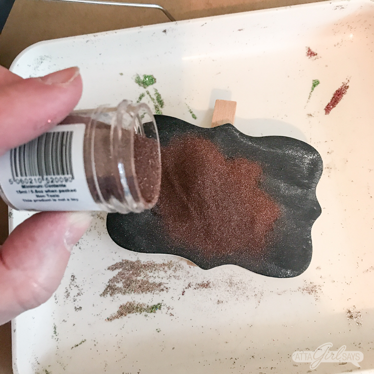 pouring embossing powder over a stamped design on a chalkboard clip