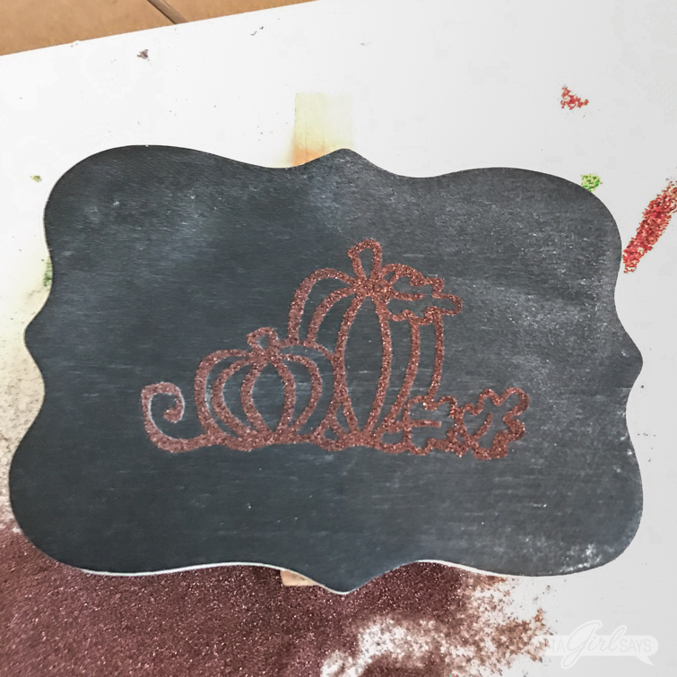 embossing powder over a stamped pumpkin design on a chalkboard clip