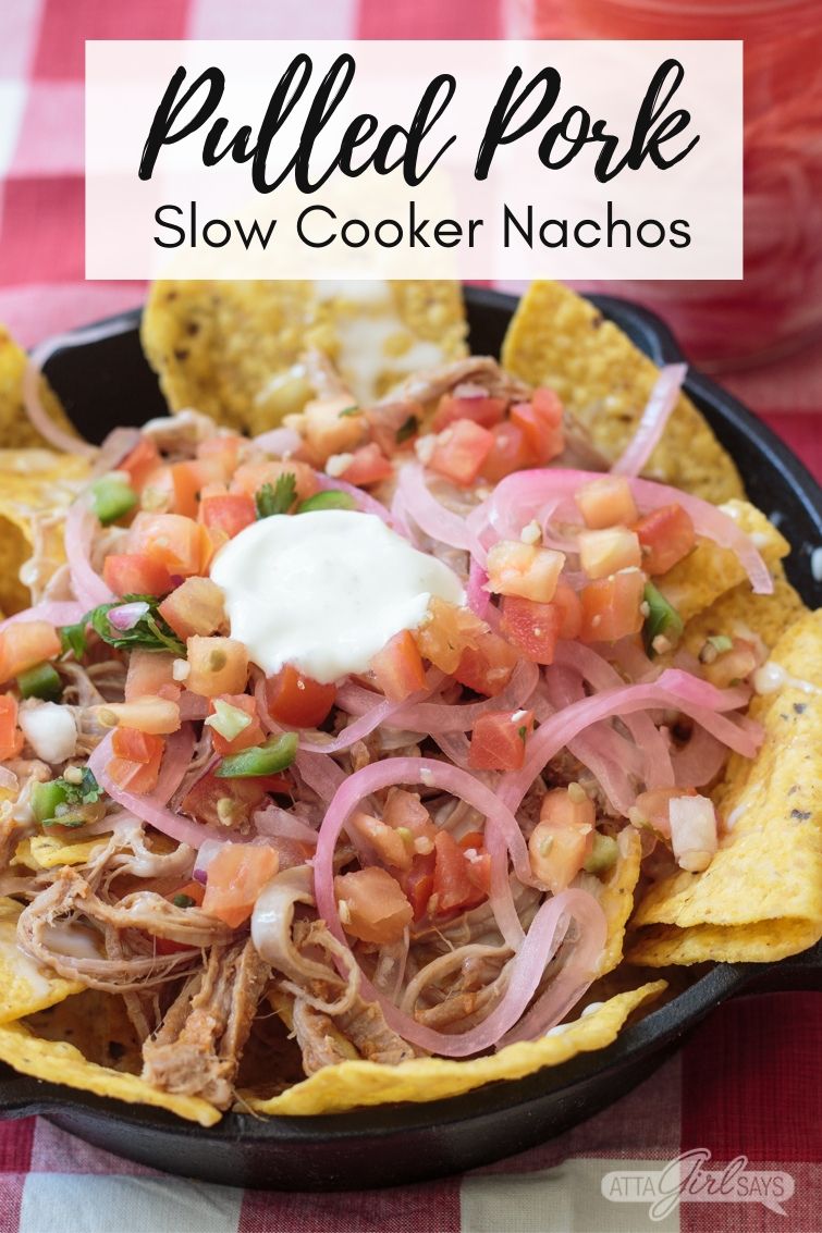 pulled pork nachos in a cast iron skillet on a gingham tablecloth