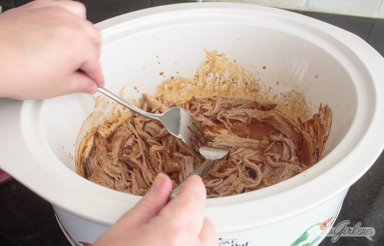 using forks to shred pork in a slow cooker
