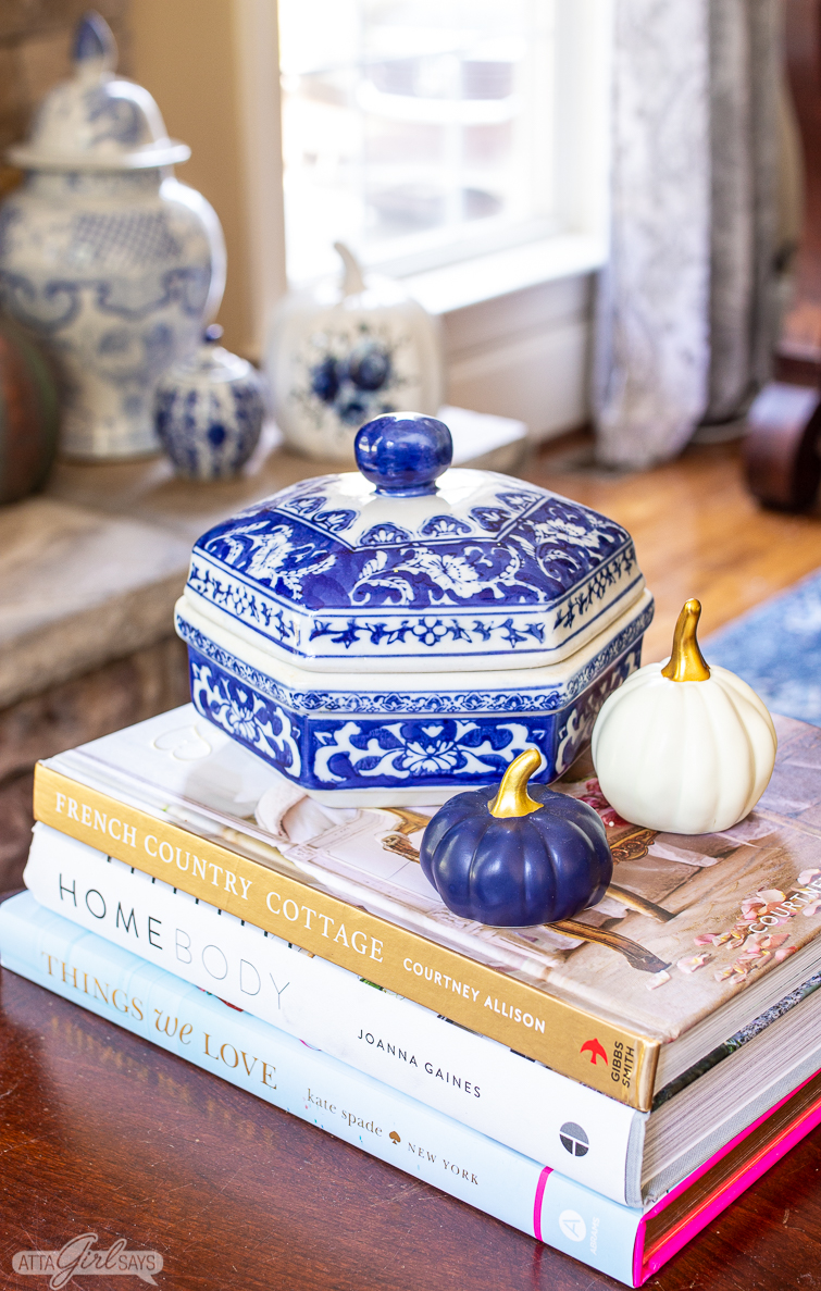 blue and white container and blue and white pumpkins sitting on home decor books