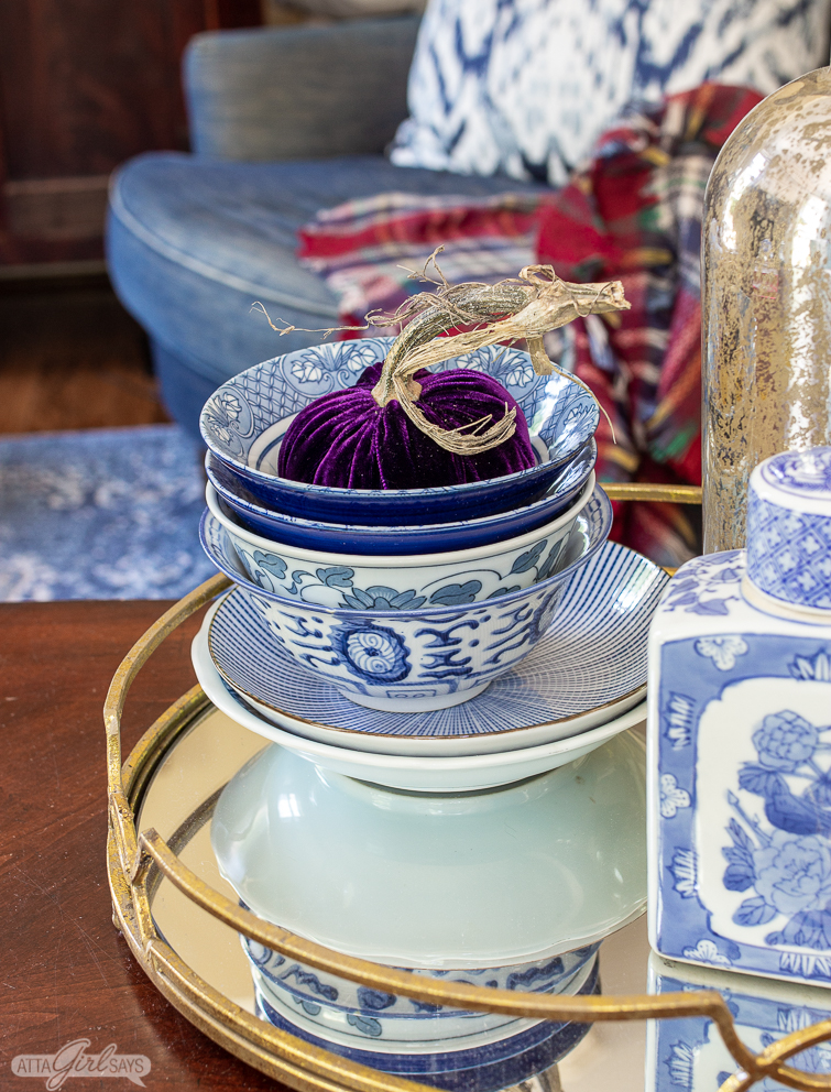 purple velvet pumpkin in a stack of blue and white bowls on a mirrored tray