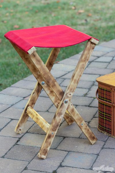 folding wood camp stool with a waxed canvas seat and a burned wood finish