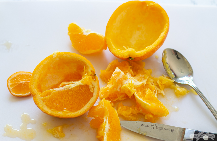 Scooping out the orange fruit to create a bowl out of the peel