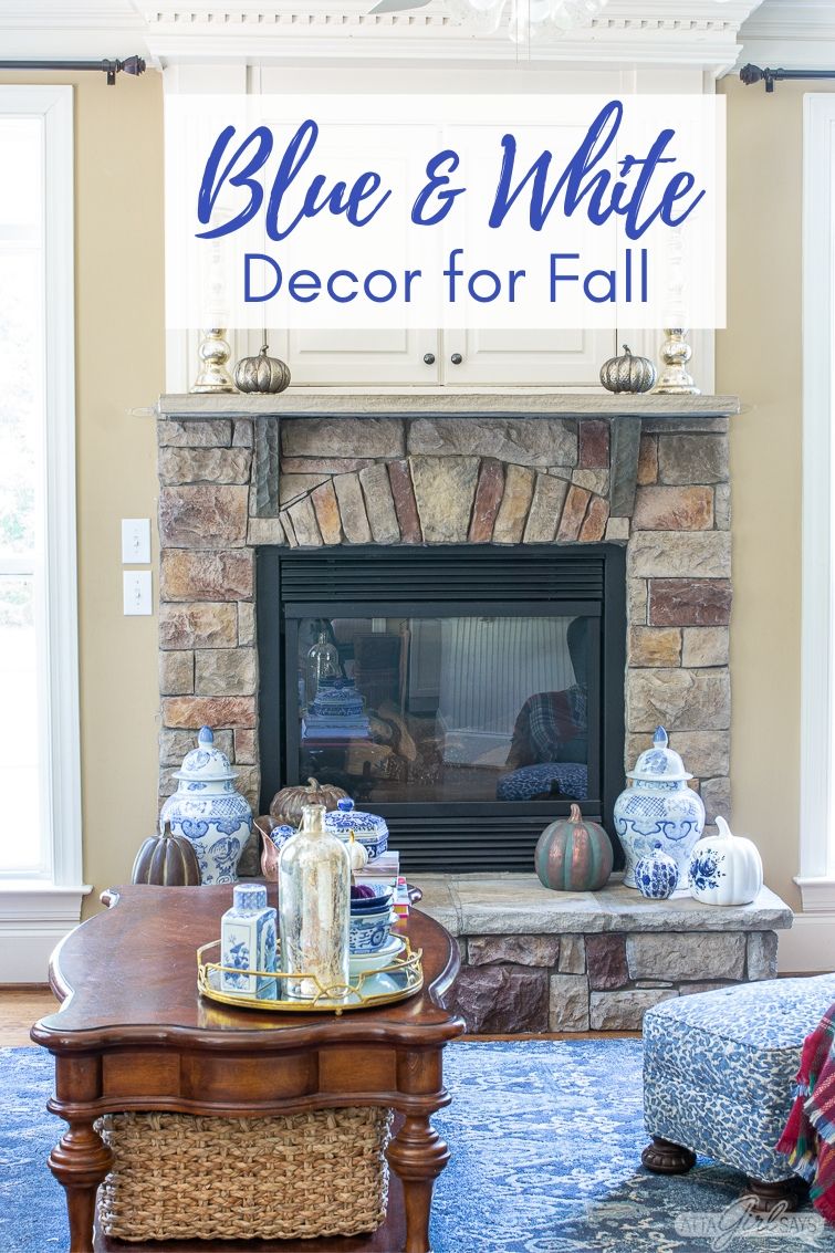 store fireplace with a TV cabinet over it decorated for fall with blue and white chinoiserie and copper pumpkins
