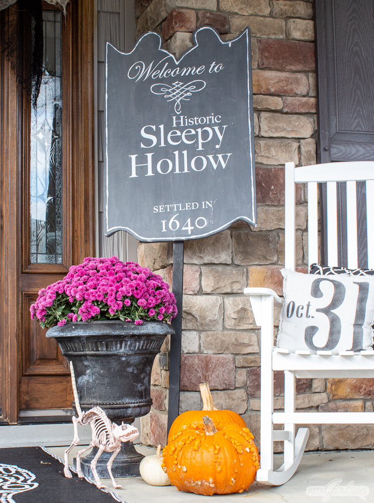 Sleepy Hollow sign, pumpkins and purple mums as front porch Halloween decorations