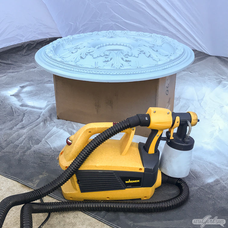 Wagner FLEXiO paint sprayer beside a painted decorative ceiling medallion