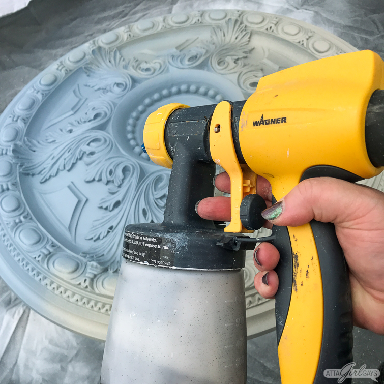 Wagner FLEXiO paint sprayer beside a painted decorative ceiling medallion