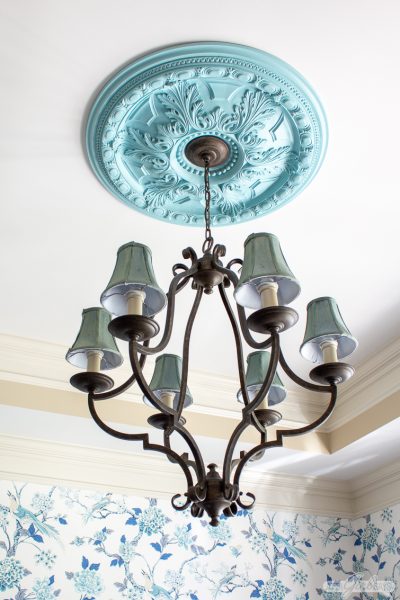 decorative aqua painted ceiling medallion hanging in a dining room with chinoiserie wallpaper
