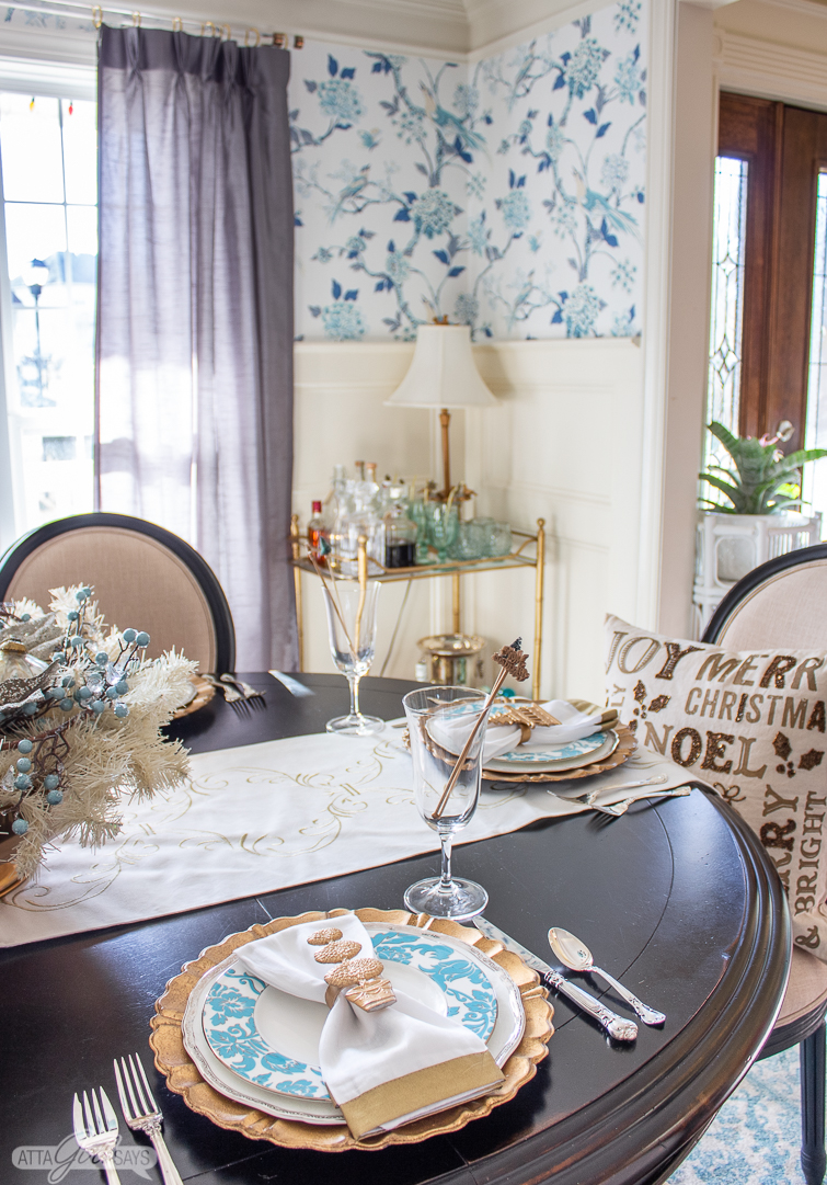 aqua blue and white plates on a holiday table with a gold bamboo bar cart in the background