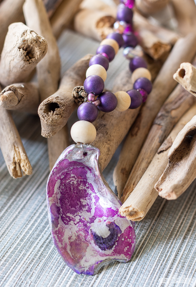 purple and silver oyster shell pendant on a wood bead necklace