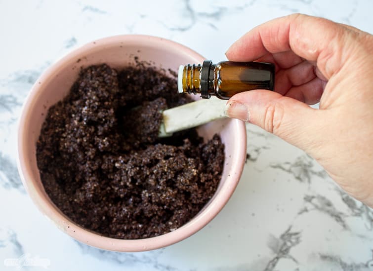 adding essential oil to coffee grounds and salt for a DIY coffee body scrub