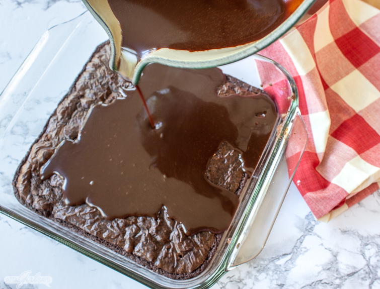 pouring homemade chocolate icing overa pan of brownies