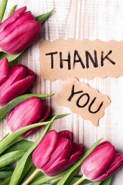Tulips on a wood background with the words Thank You written on paper