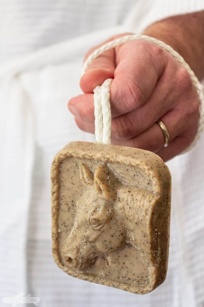man wearing a bathrobe holding a bar of soap on a rope