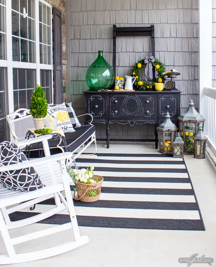 black buffet and white glider bench on a front porch with lemon yellow and green decorative accents