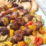 pork and vegetable kabobs over orzo pasta on an enamel tray