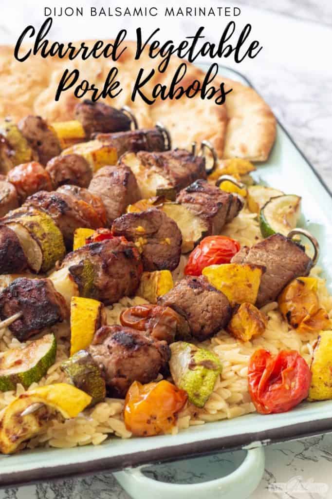 pork and vegetable kabobs over orzo pasta on an enamel tray