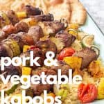 pork and vegetable kabobs over orzo pasta on an enamel tray