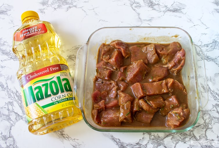 pork tenderloin marinating in a pyrex dish beside a bottle of Mazola corn oil