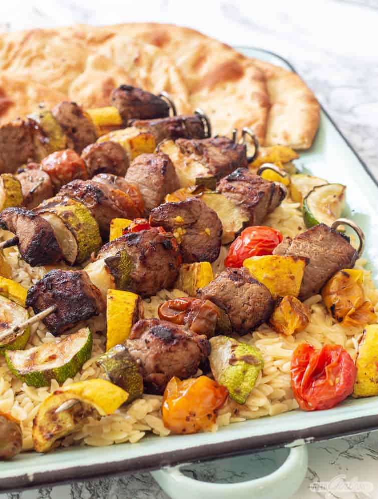 Dijon Marinated Pork Tenderloin Kabobs with Charred Vegetables over orzo on a platter