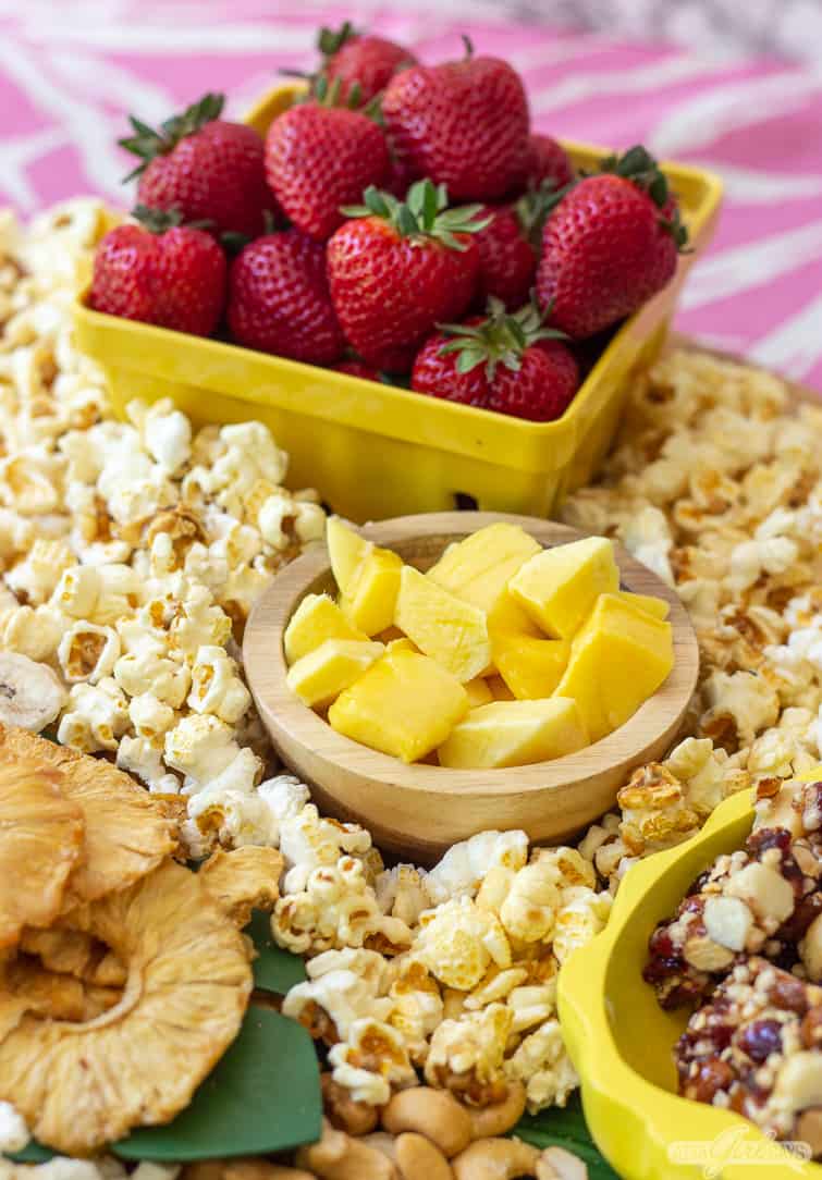 mango and strawberries and popcorn on a snack board