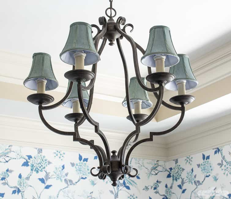 wrought iron chandelier with blue shades in a dining room with chinoiserie wallpaper