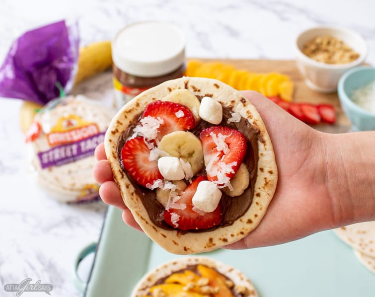 boy's hand holding a strawberry-banana s'mores taco with Nutella