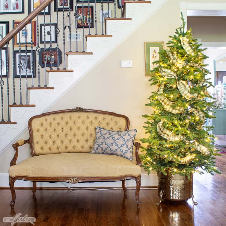 Christmas tree in a vintage brass planter beside a yellow French style settee