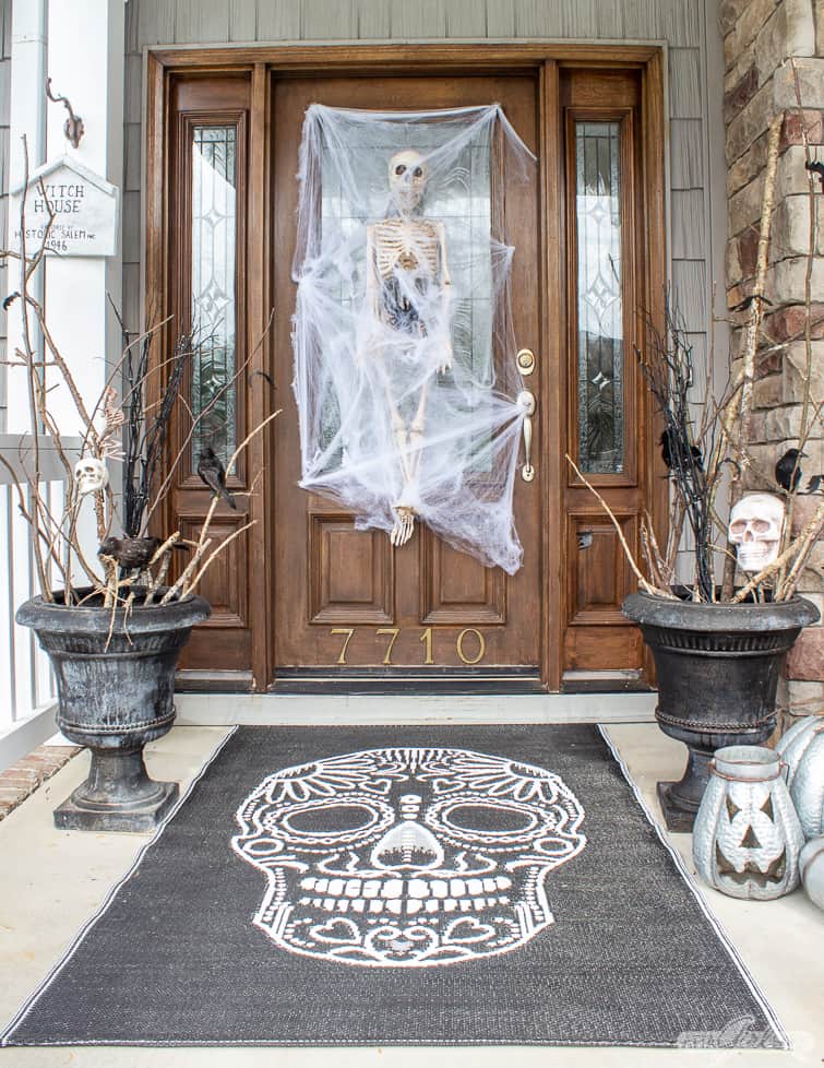 skull rug and skeleton on a front door for Halloween porch decorations