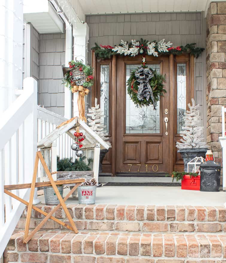 white trees in planters and a fresh evergreen wreath on the front door