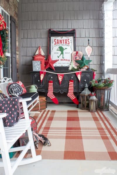 Christmas porch with a black buffet decorated with vintage items and a red and white plaid rug