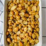 roasted potatoes with capers and olives in a white baking dish