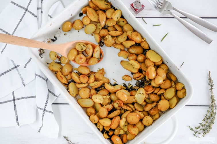 serving herb roasted potatoes with a wooden spoon