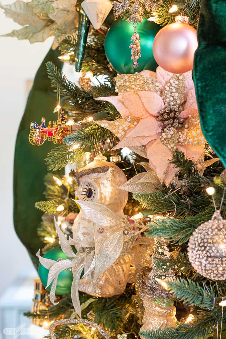 pink poinsetta floral pick and oversized glass owl ornament in a Christmas tree