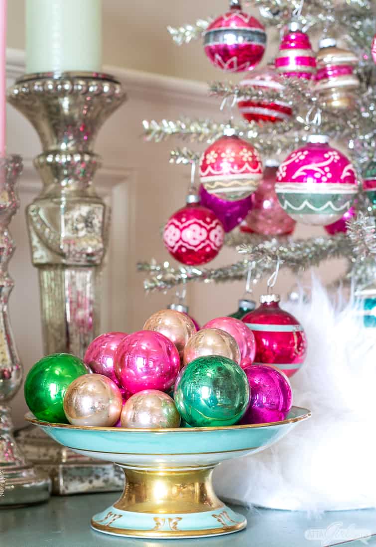 pink and green vitage ornaments in an aqua blue compote beside a tabletop tinsel tree