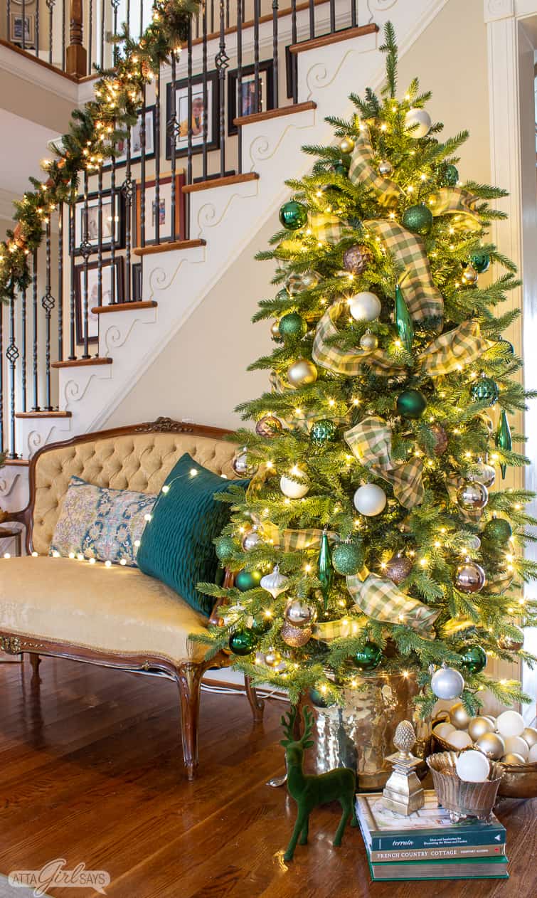 Christmas tree in a brass planter beside a tufted back yellow French settee