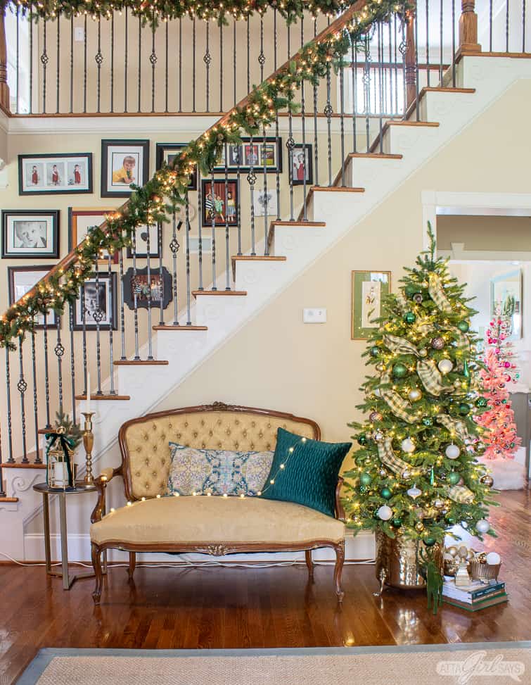Christmas tree in a brass planter beside a tufted back yellow French settee