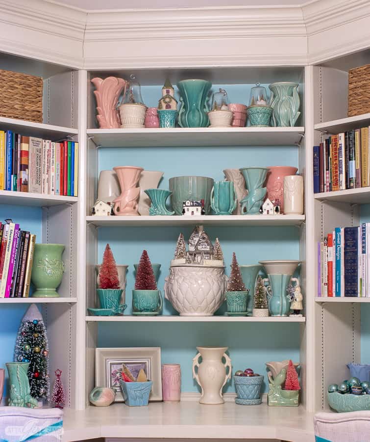 built in bookcases painted aqua and white decorated with vintage pastel McCoy pottery for Christmas