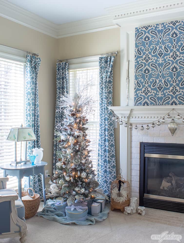 flocked Christmas tree beside a fireplace in a bedroom