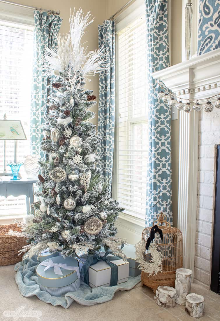 flocked Christmas tree beside a fireplace in a bedroom