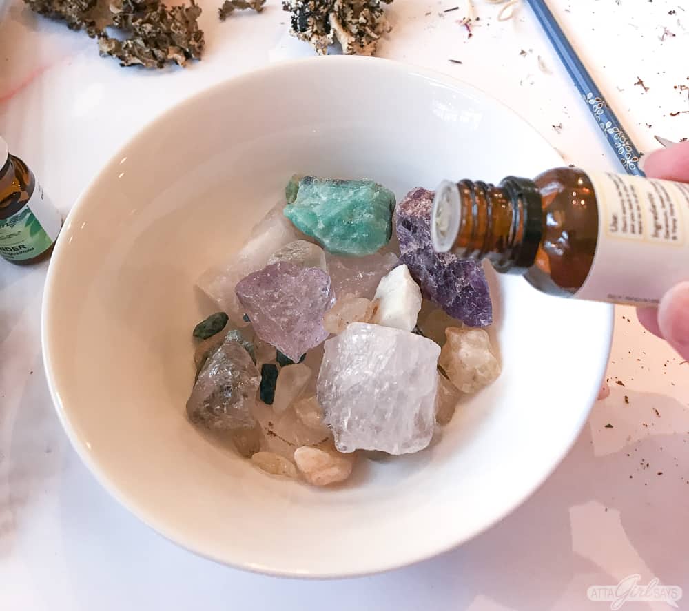 adding essential oil fragrance to gemstone rocks in a bowl to make homemade potpourri
