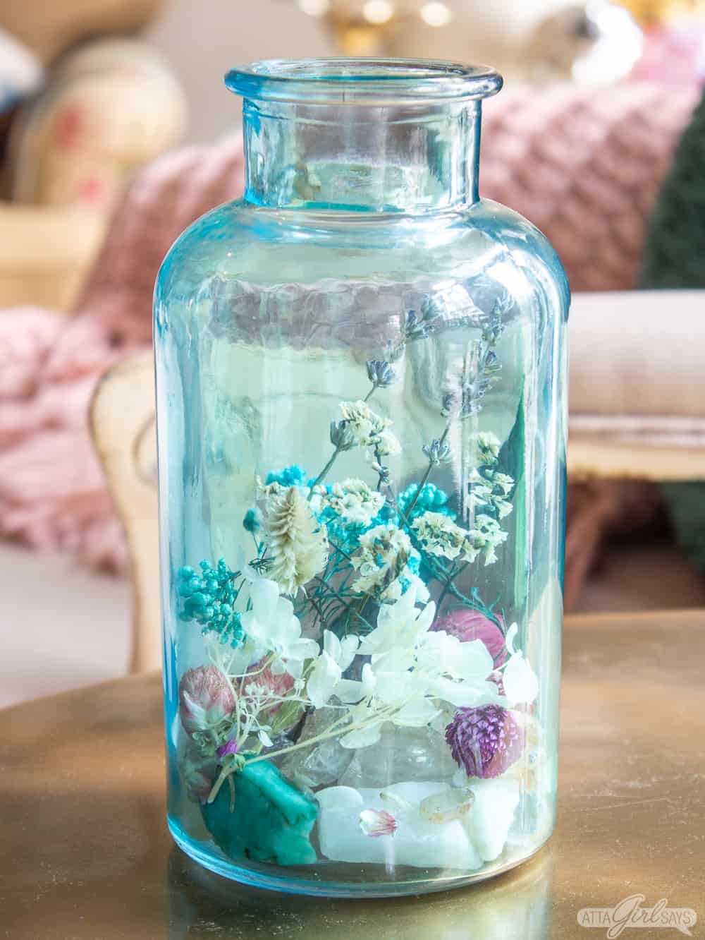 aqua blue glass jar filled with dried florals and gemstone rocks homemade potpourri